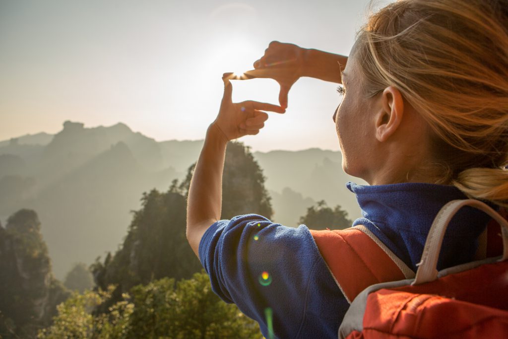 Young woman framing mountain landscape with hands